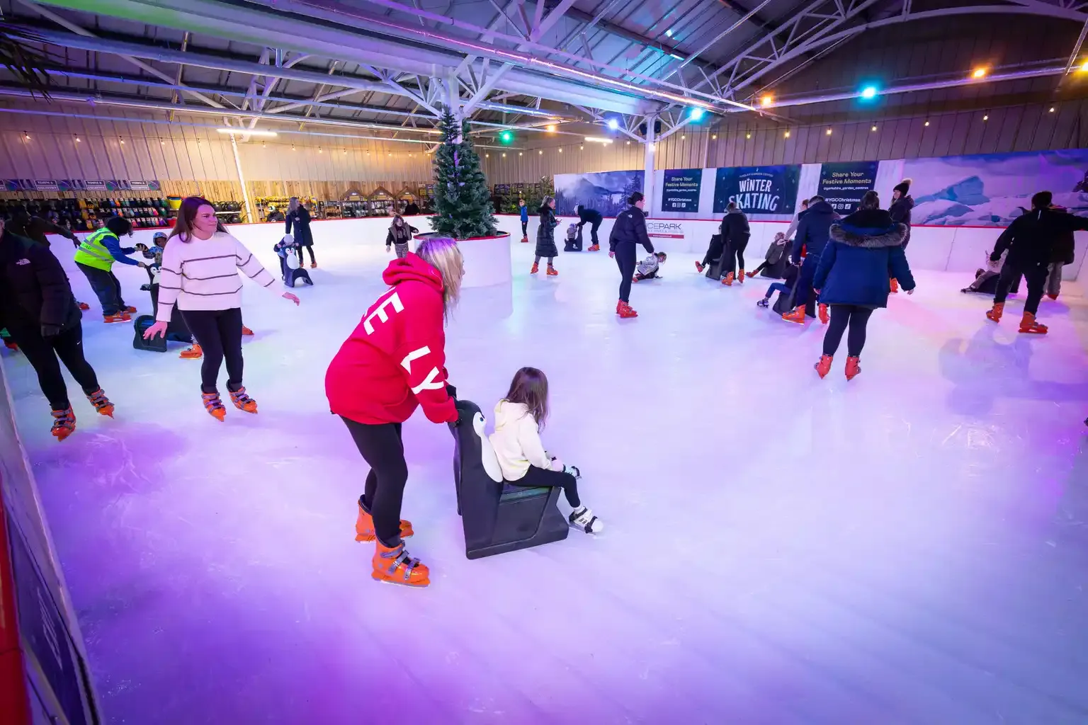 Skaters enjoying the covered real ice rink under festive lights at Tingley Garden Centre