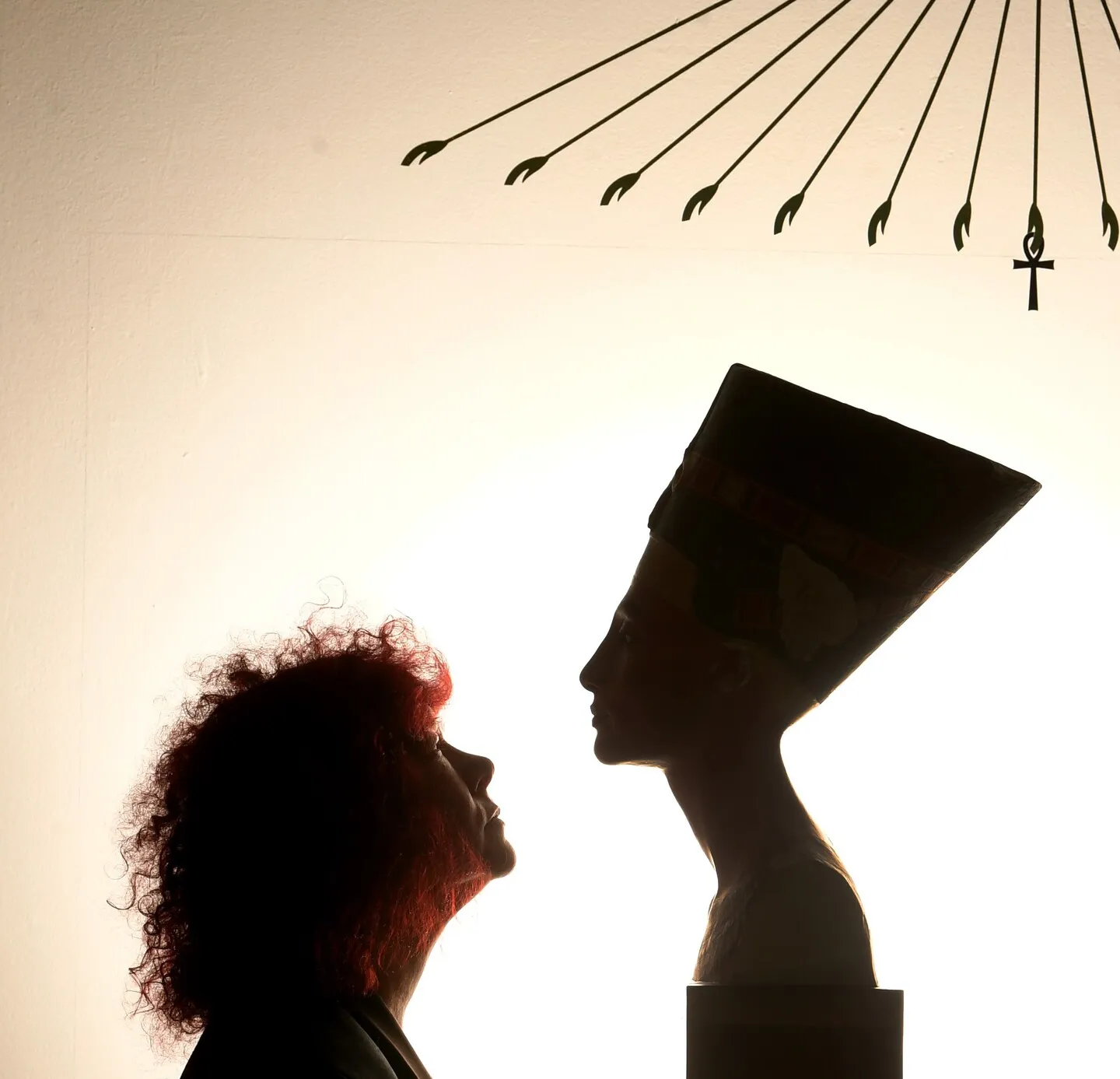 bust of cleopatra with a person looking at it, both in side pofile and silhouetted to the camera