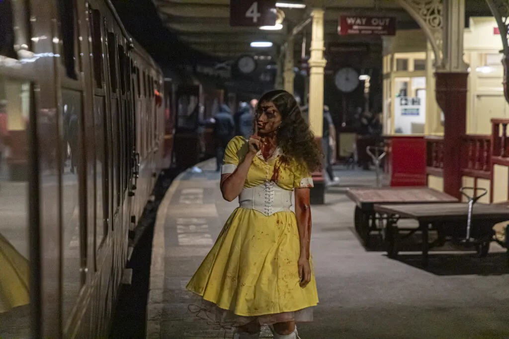 Scary halloween character on a Keighley and Worth valley station platform looking at the train, character wears a yellow dress