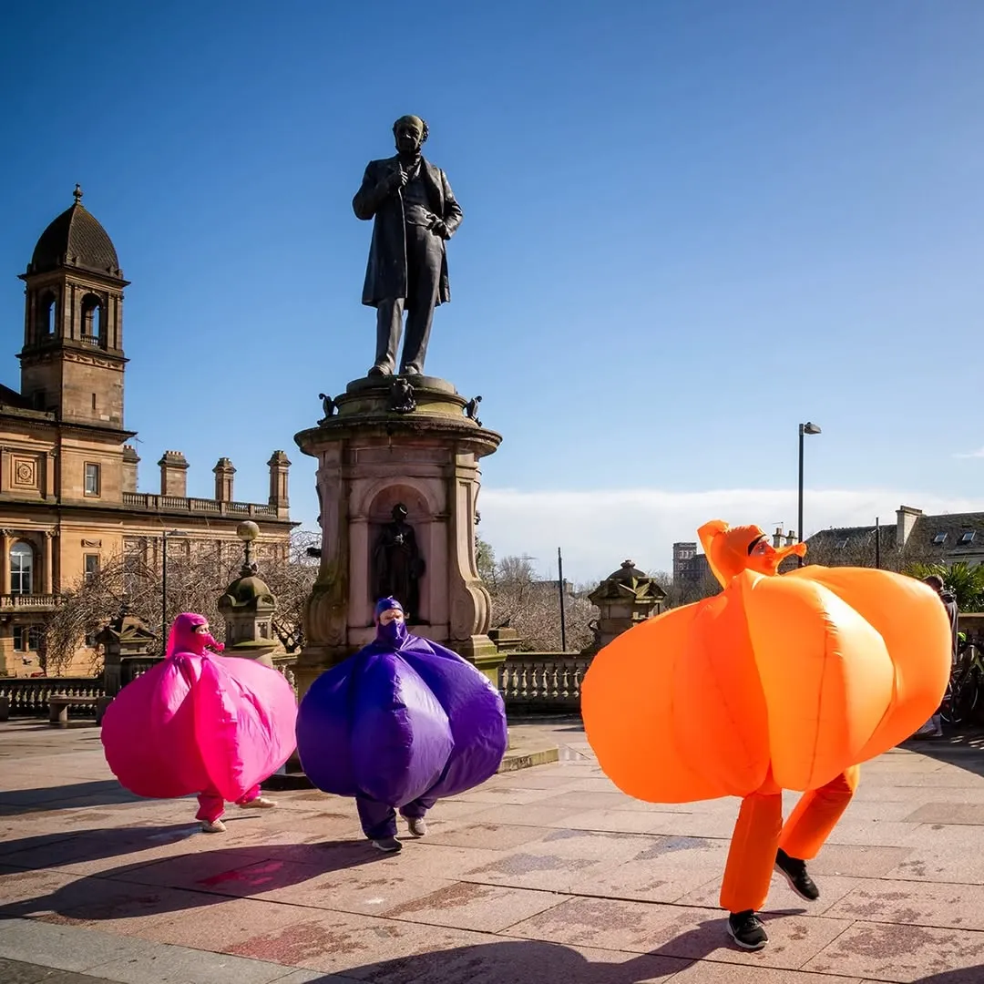 Windbags, three people in brightly coloured inflatable costumes, purple, pink and orange part of the entertainment at Bradford Festival in July