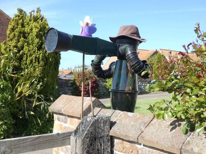 man made from flowerpots looking through a flowerpot telescope at the Flamborough Flowerpot Festival in June 2026