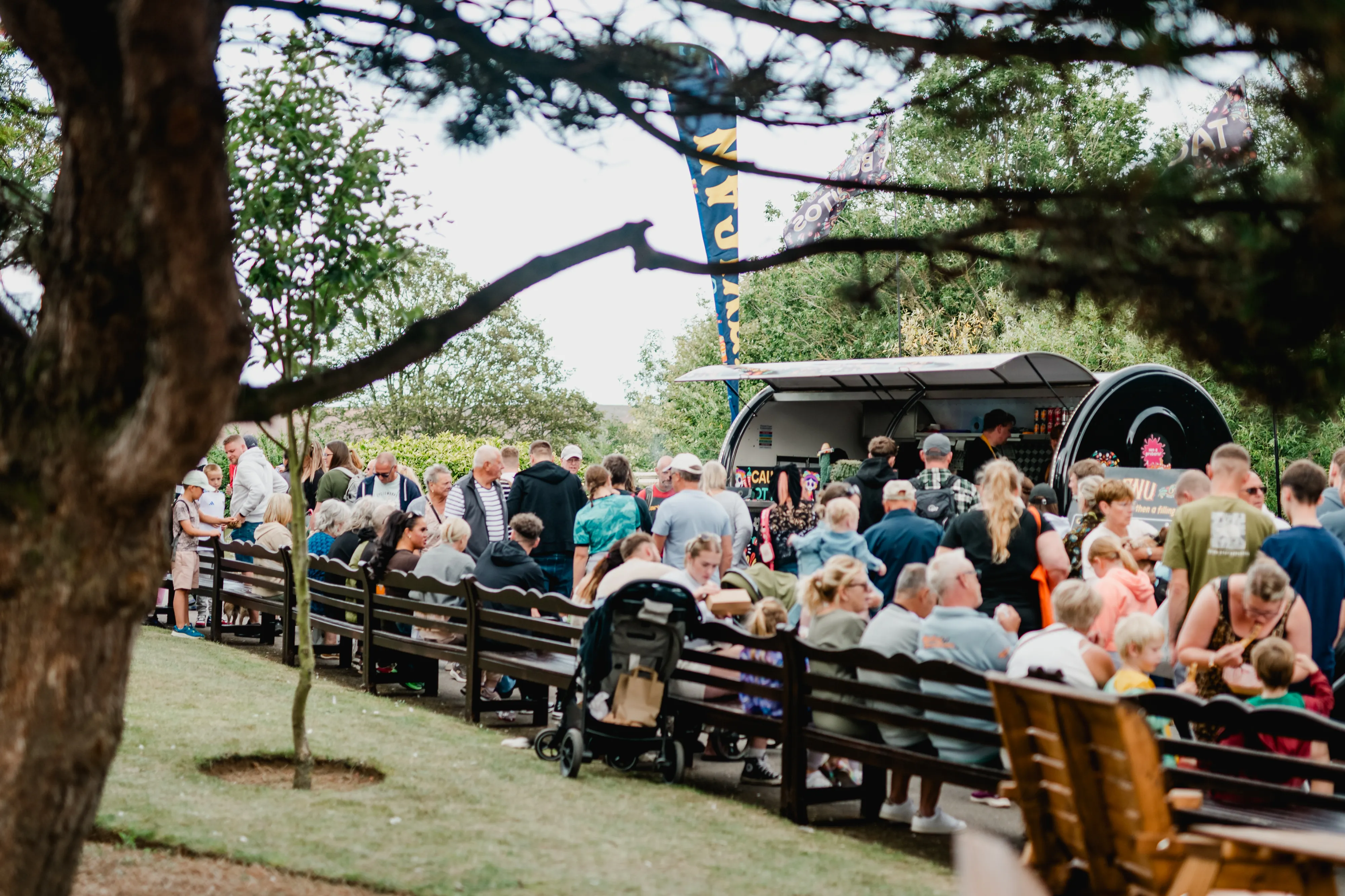 people on Filey promenade seated on benches and enjoying the stalls at the Filey Food Festival