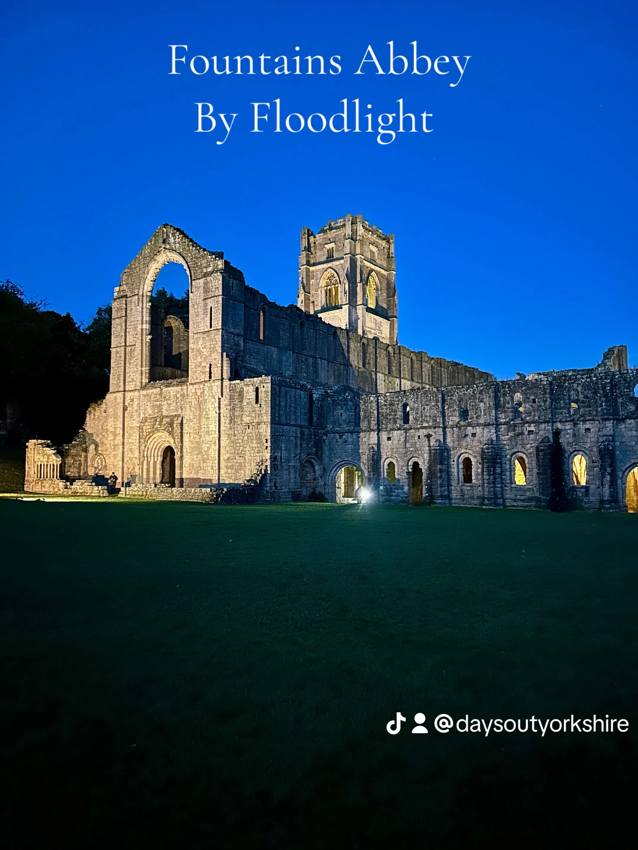 Illuminated ruins of Fountains Abbey glowing under floodlights at night near Ripon