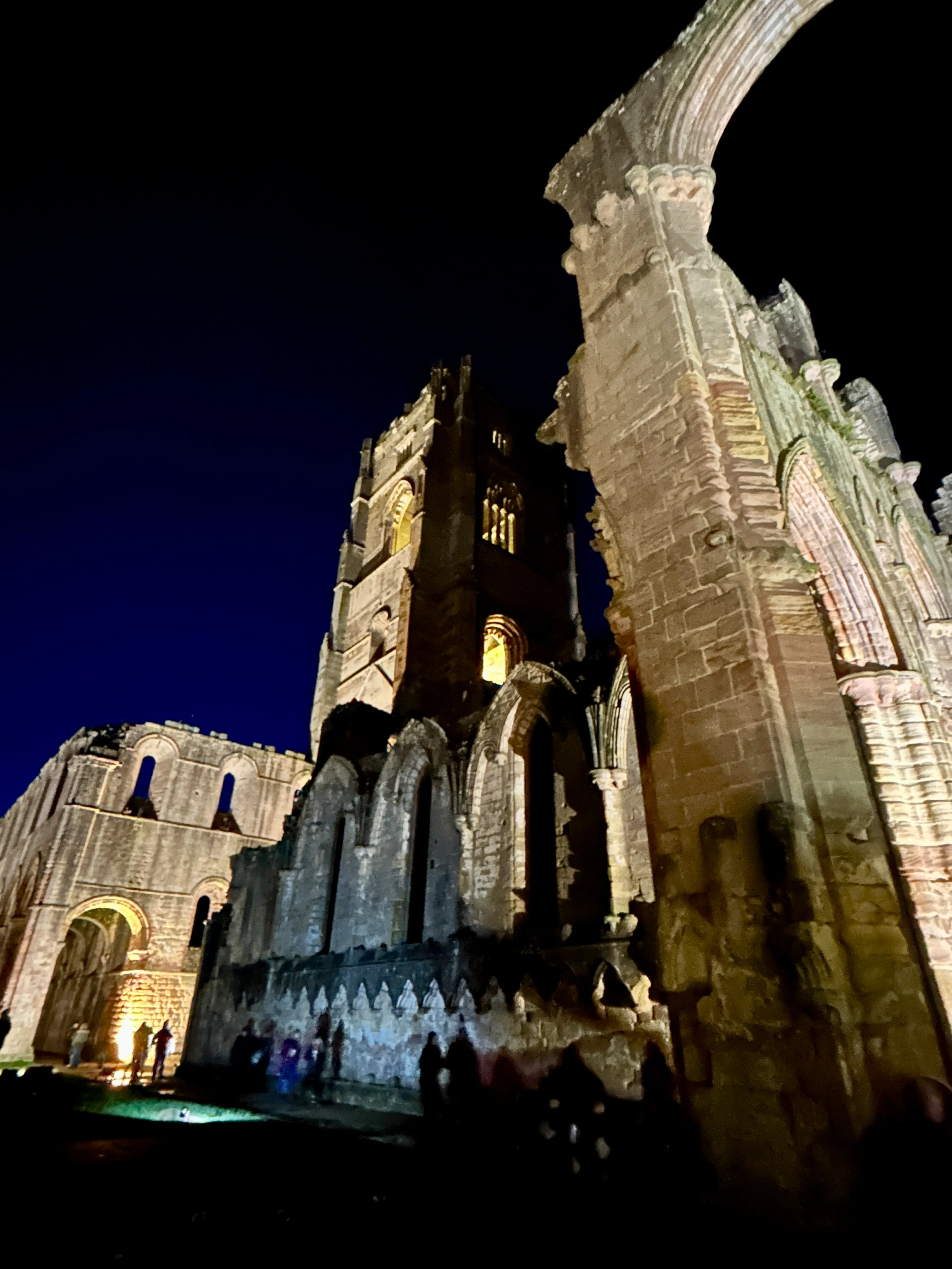 Visitors exploring the illuminated grounds at the Fountains Abbey by Floodlight event