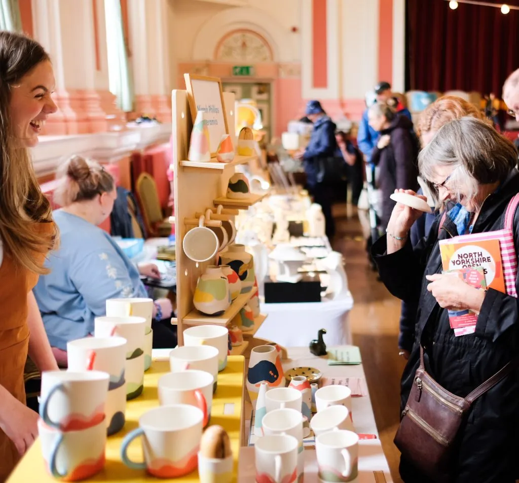 Trader and customer laughing and enjoying the Saltaire Winter Makers Market in October 2026