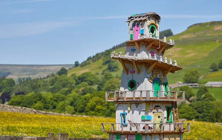 Brightly coloured multi-storey fairy house on the studfold adventure trail with views of the nidderdale valley beyond.
