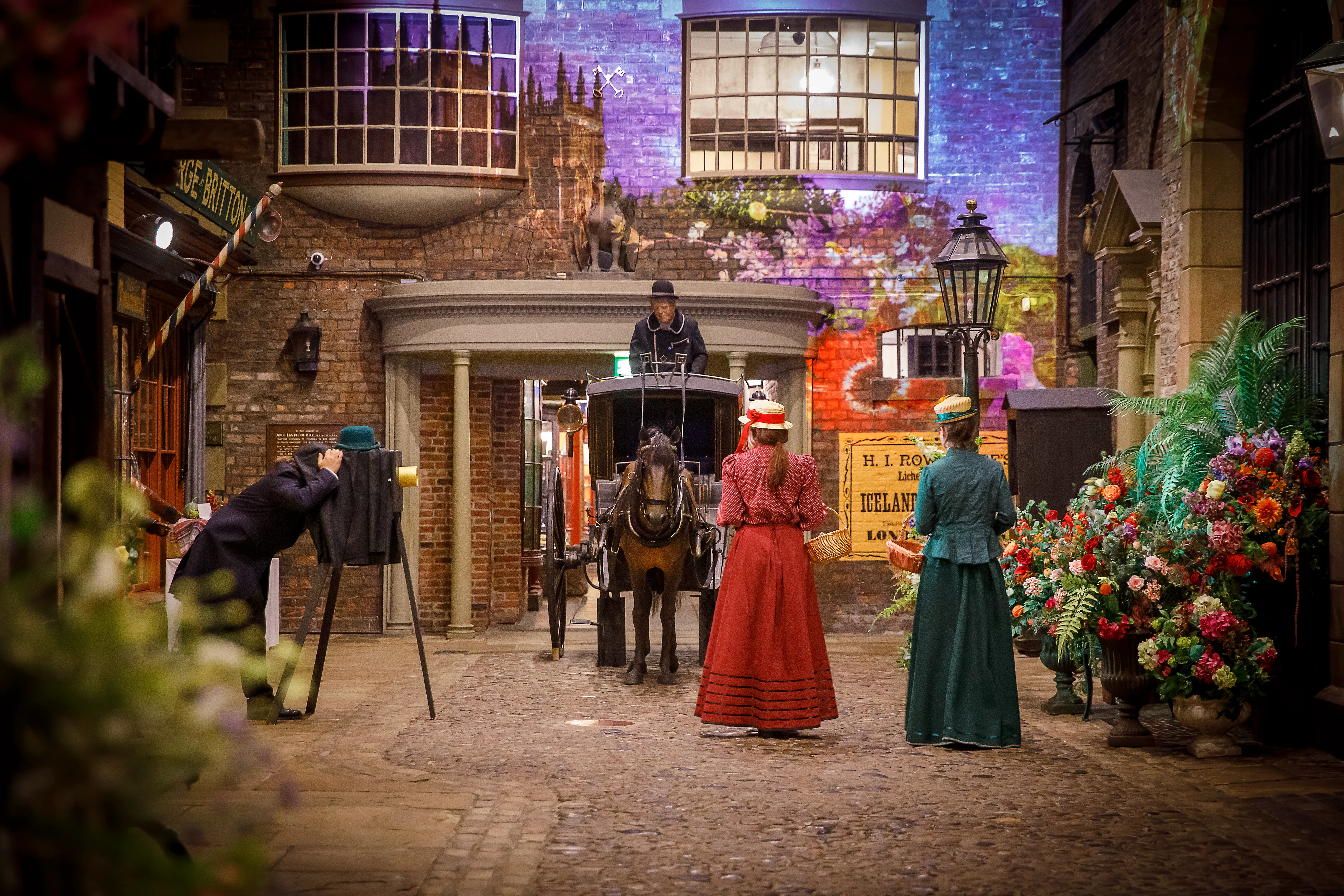 Kirkgate Victorian street at York Castle, with people in period dress and a projection of hot air balloons for the York Castle Museum Summer event