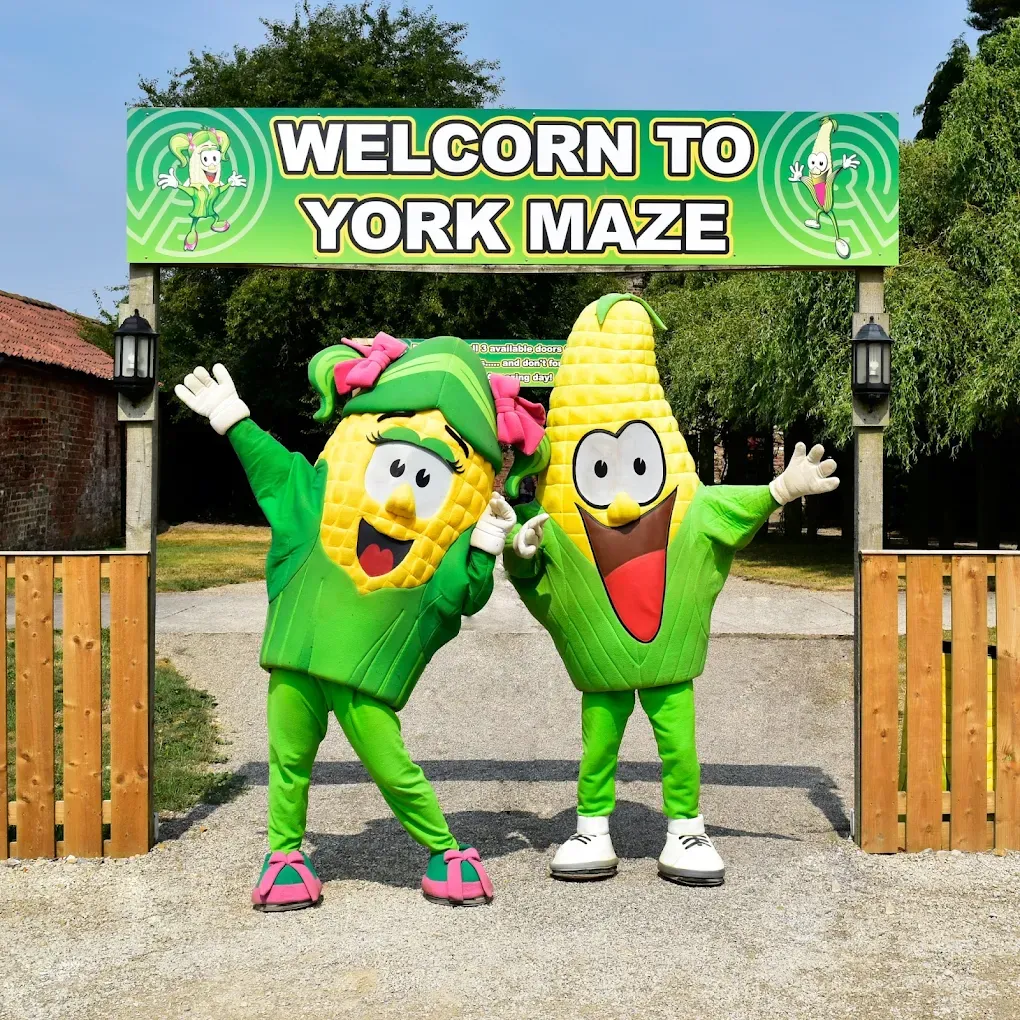 Corn mascots at York Maze under a welcome sign.