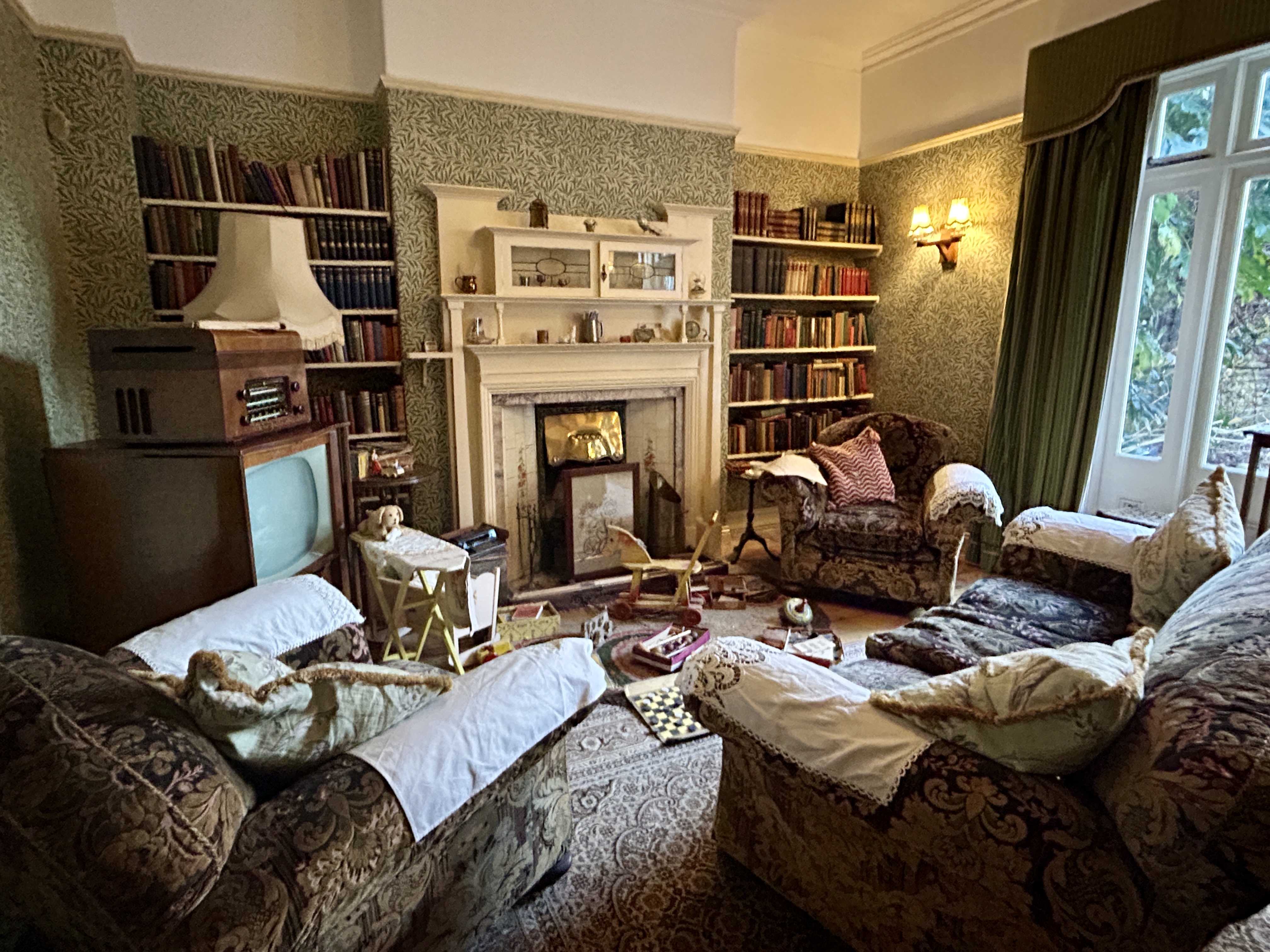 1940s interior of the living room of Alf Wight author of the JAmes Herriot novels. With an armchair and sofa, tv set, books opf shelves in the alcove of the fireplace and children's toys on the floor.