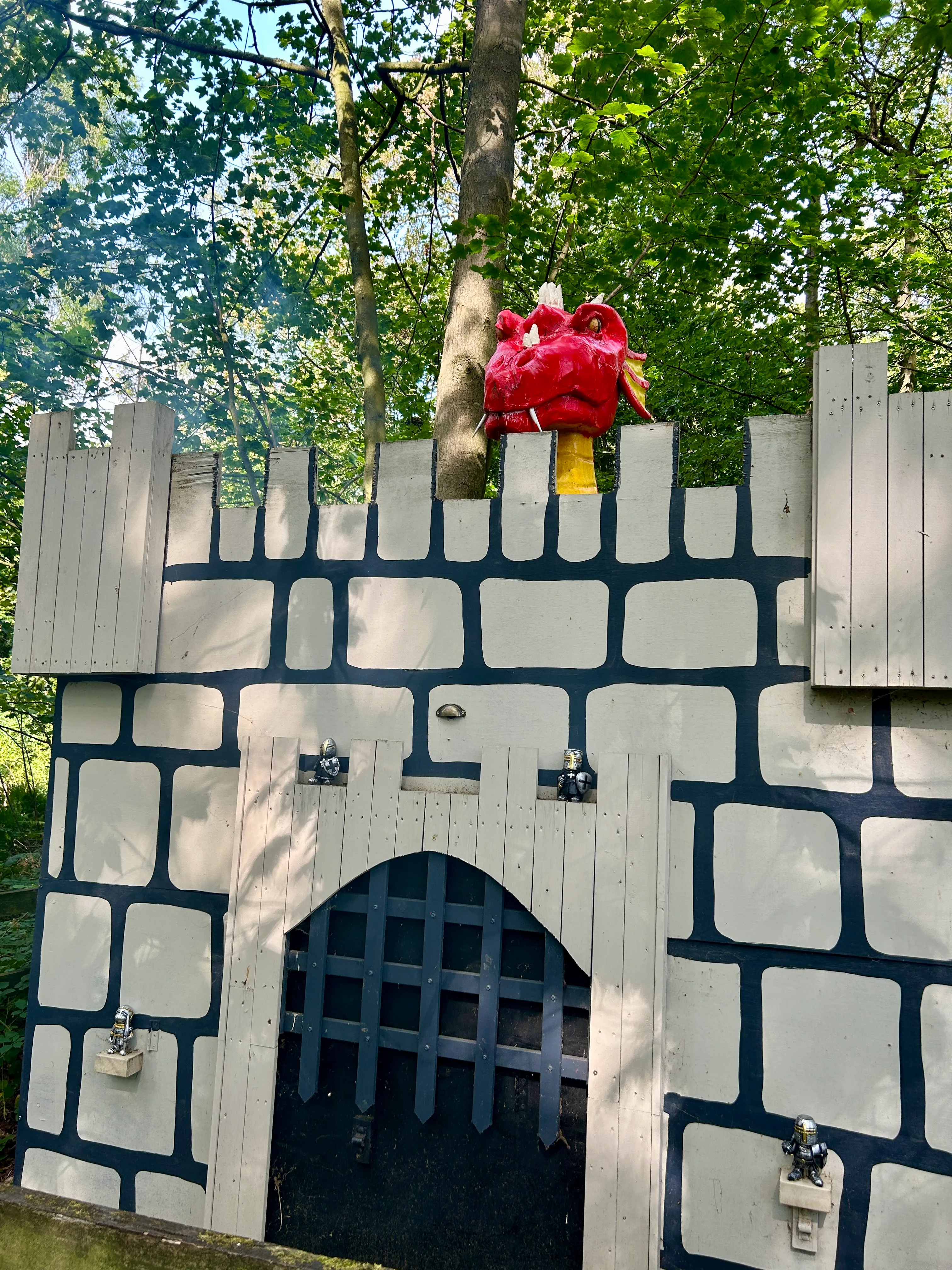 Red dragon looking out from over a grey castle in the Secret Forest.
