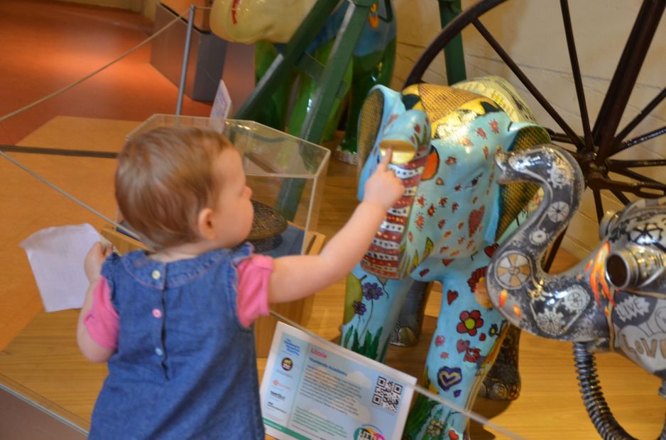 Toddler reaching out to touch a ceramic elephant