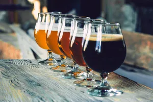 row of beers and drinks in stemmed glasses on a wooden bar