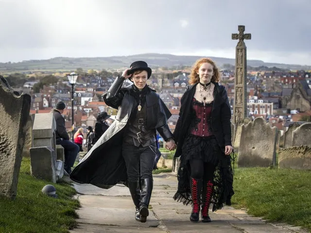 man and women in gothic clothing at the top of the 99 steps in whitby