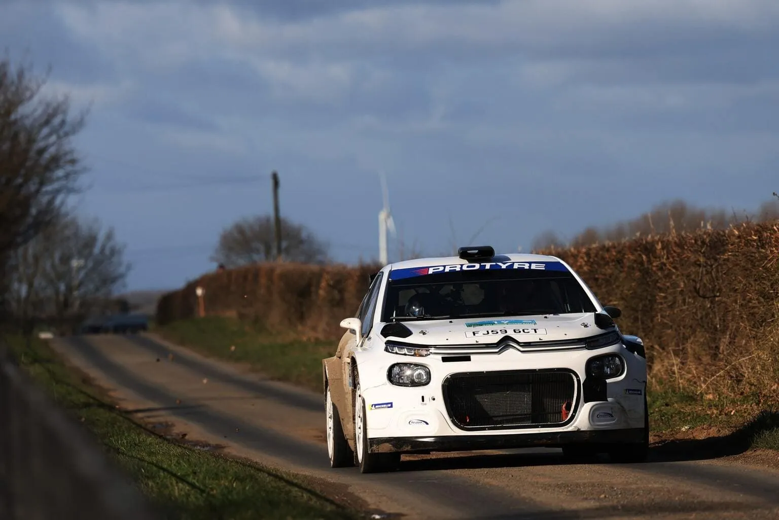 White rally car with open road behind