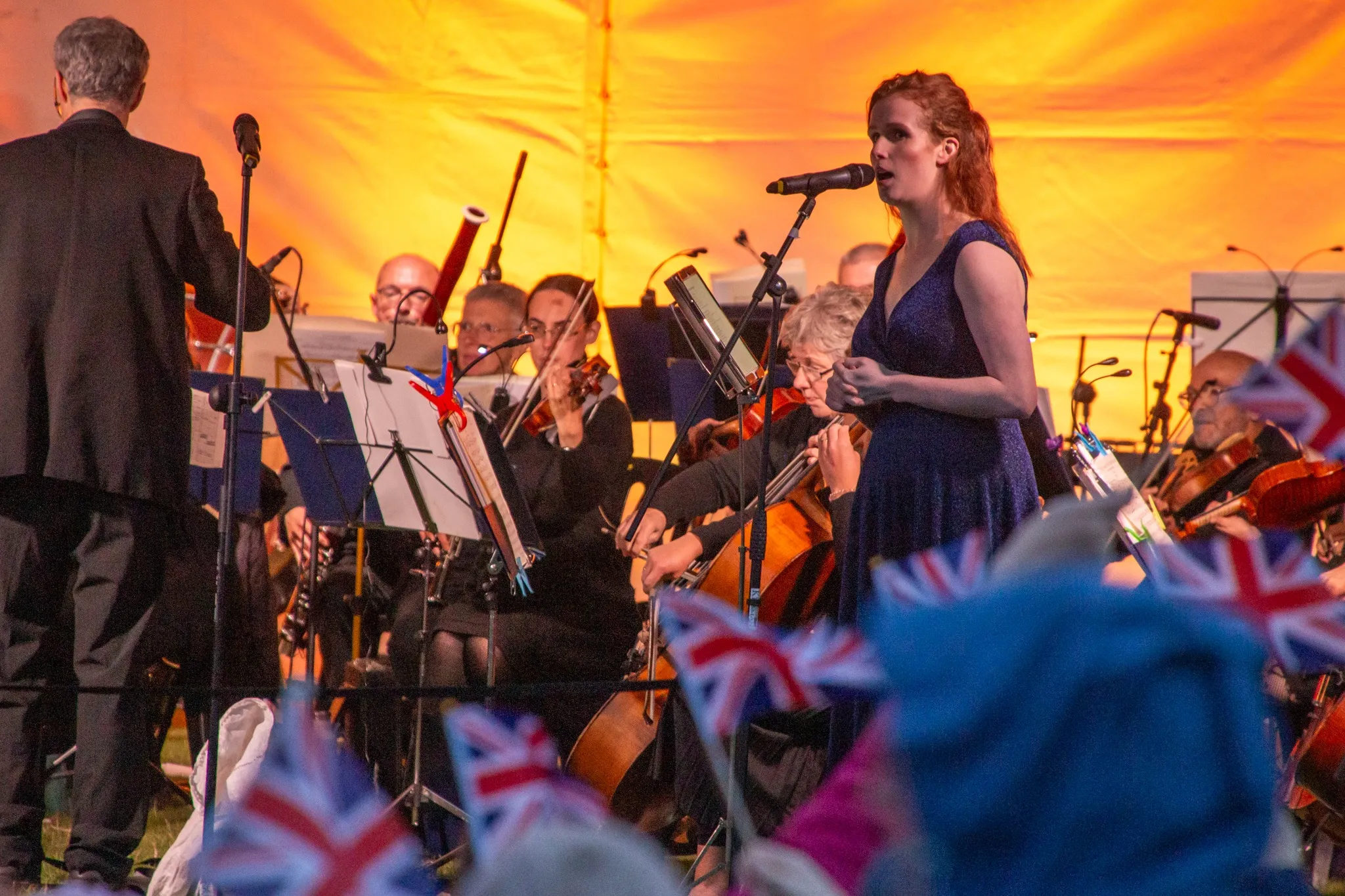 Lady in a blue dress singing, surrounded by the orchestra at the Pontefract Castle Proms in the castle event in June.